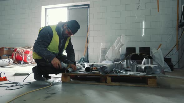 An Employee Cuts an Iron Pipe with a Bulgarian Knife