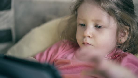 Portrait of a Pretty Little Girl, a Child Who Lies on the Sofa Under the Blanket