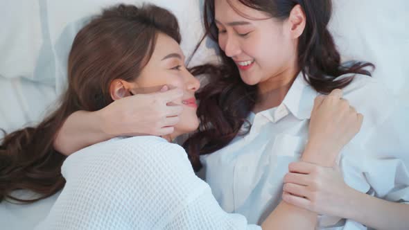 Asian beautiful lesbian couple lying down on bed and hugging each other.