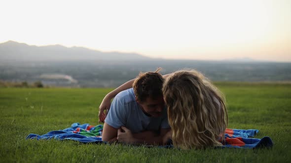 Shot of cute boyfriend and girlfriend laying on a blanket and having a picnic on the grass. The coup