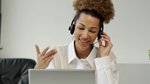 A Smiling AfricanAmerican Call Center Agent Wearing Headphones with a Microphone Talking to a Client