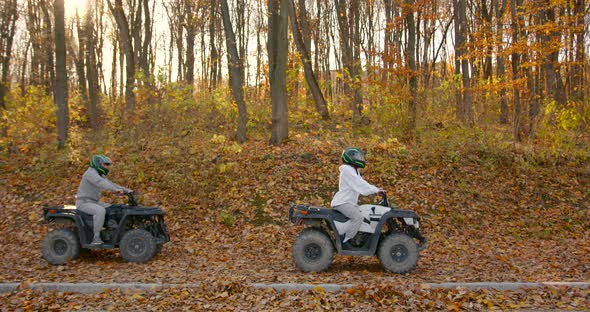 A Young Couple Rides an ATV Offroad in the Autumn Forest