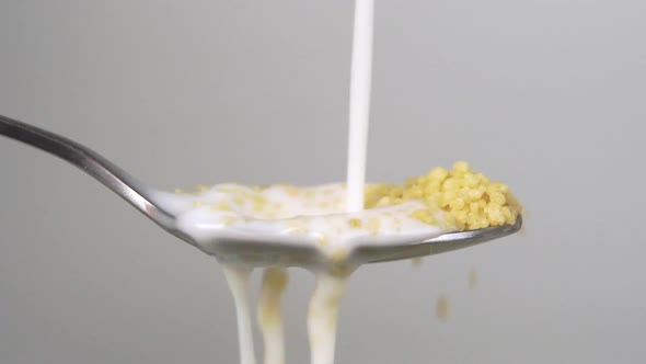 Milk is poured in slow motion into a spoonful of raw couscous