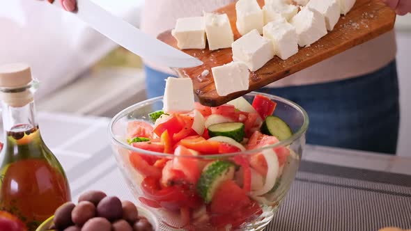 Greek Salad Preparation Series Concept  Woman Pouring Sliced Feta Cheese Into a Bowl