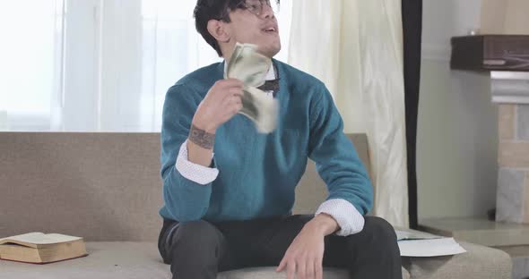 Rich Caucasian Guy in Eyeglasses Counting and Scattering Money As Sitting on Couch. Wealthy Young