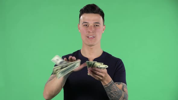 Portrait of a Handsome Young Guy Is Looking at Camera and Scattering Dollars with Proud Haughty