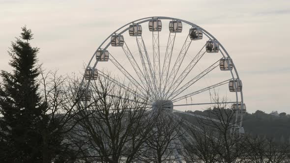 White Ferris Wheel Cabinets Spinning, Bare Trees On Foreground - wide shot