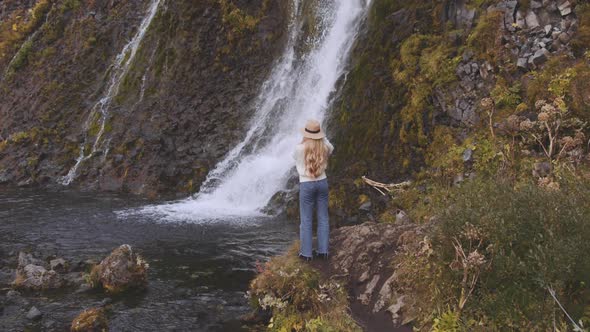 Woman Photographing Waterfall From Riverbank