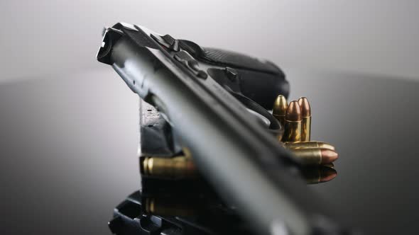 Gun Control. 9mm handgun with bullets rotating on a reflective surface