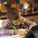 A Cute Boy of 7 Years Old Sits in the Kitchen at the Table Looks at the Desktop Monitor - VideoHive Item for Sale