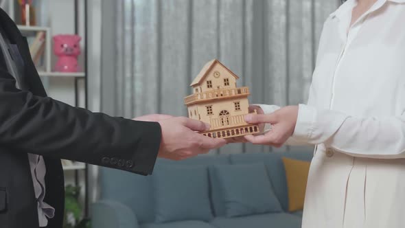 Close Up Of Real Estate Agent's Hand Giving A House Model To A Woman In The House For Sale