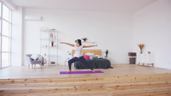 Young Female Doing Yoga in VR Glasses at Home