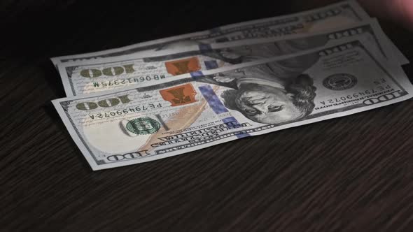 Counting New Hundred Dollar Banknotes on a Black Wooden Table