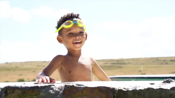 African Boy Splashing Water in Outdoor Pool