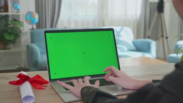 Asian Woman Wearing A Graduation Gown And Cap Use Laptop Computer With Green Mock-Up Screen