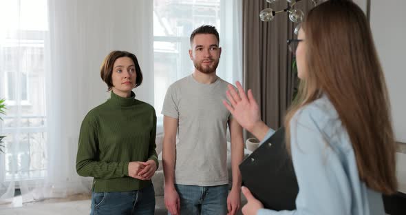 Close Up of Real Estate Agent Woman Shows Modern House to a Young Couple