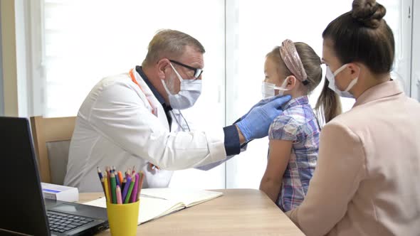 Little Girl with Her Mother at a Pediatrician Appointment, Elderly Male Pediatrician Examines 