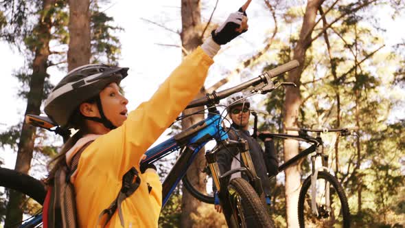 Mountain biking couple carrying bicycle and pointing at nature