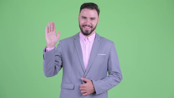 Happy Young Handsome Bearded Businessman Waving Hand