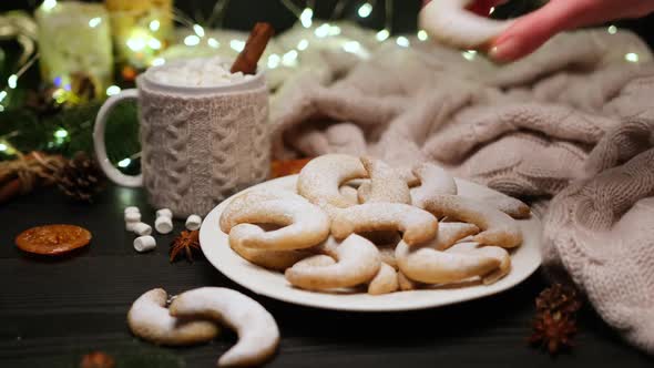 Woman Puts Traditional German or Austrian Vanillekipferl Vanilla Kipferl Cookies on a Plate