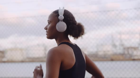 Young Woman In Sportswear And Headphones Jogging Along Harbour