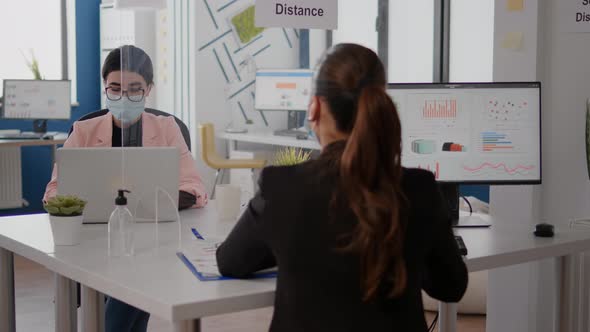 Freelancer Talking with Coworker About Business Startegy While Sitting in New Normal Office