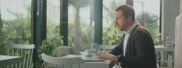 Man working on laptop in empty cafe