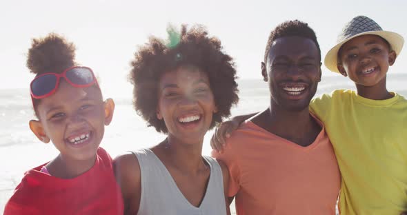 Portrait of smiling african american family embracing on sunny beach