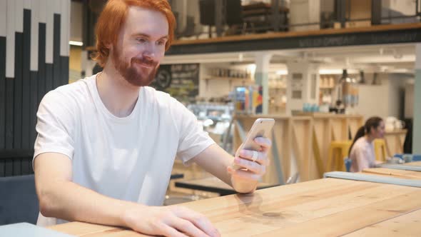Astonished, Amazed Redhead Beard Man Using Phone in Cafe