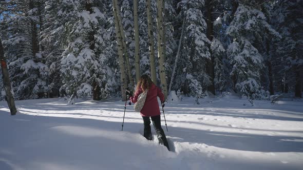 Girl walking through the snow with snowshoes.