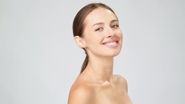 Beautiful Young Woman with Clean Fresh Skin Standing Over Light Grey Background