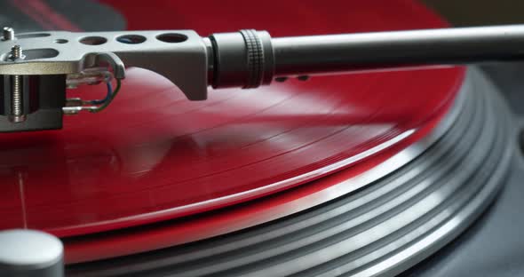 Red music record spinning close-up - listening to music on gramophone vinyl