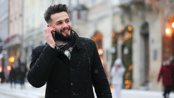 A Man is Going in the Central Square in a Snowfall