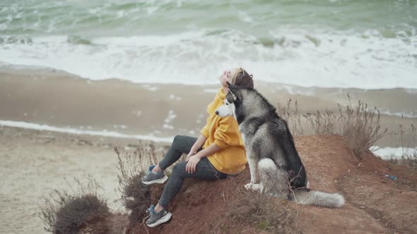 Young Beautiful Female Walking with Siberian Husky Dog on the Beach