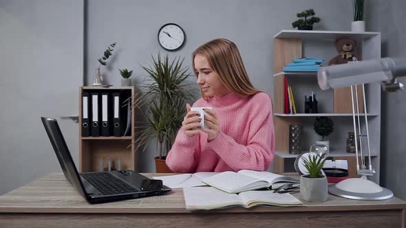 Young Girl in Knitted Sweater which Posing on Camera with Cup of Tea During Work