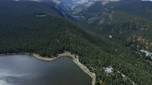 Aerial view panning up from alpine lake to snowy mountains in distance, 4K