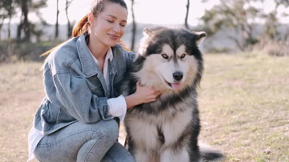 Pretty Girl Is Walking with a Cute Fluffy Dog in the Field