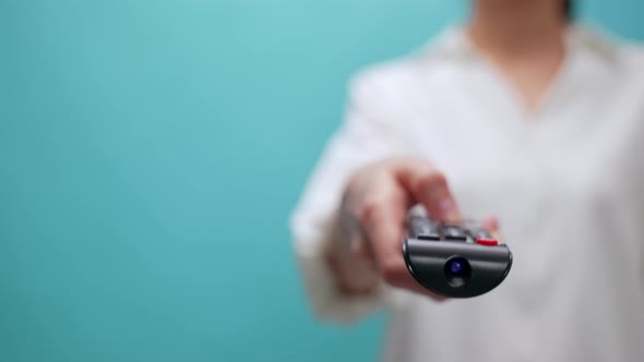 Woman holding the TV remote to watch movies on the blue background