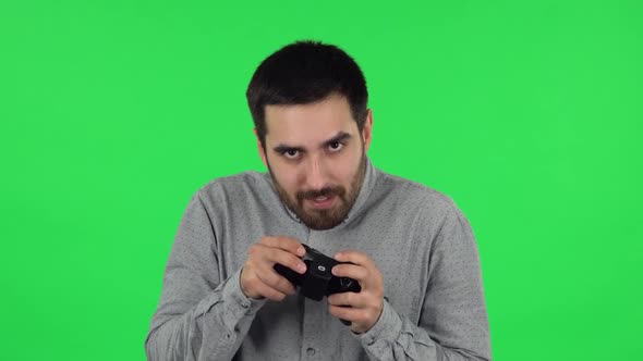 Portrait of Brunette Guy Is Playing a Video Game Using a Wireless Controller and Loses. Green Screen