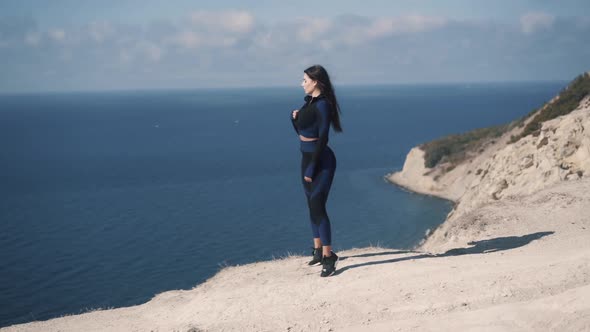 Cute Young Caucasian Girl Athlete and Unbuttoning a Jacket Standing on Seashore