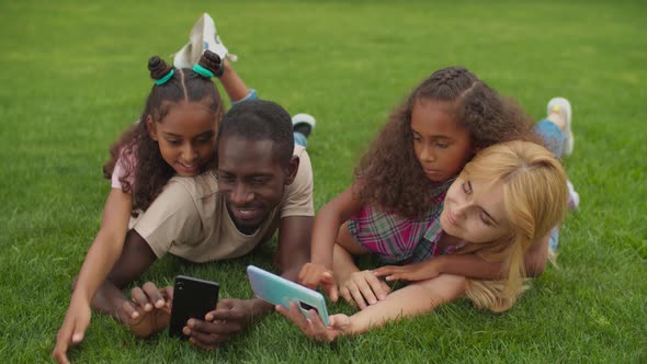 Multiracial Family Taking Selfie Lying on Grass