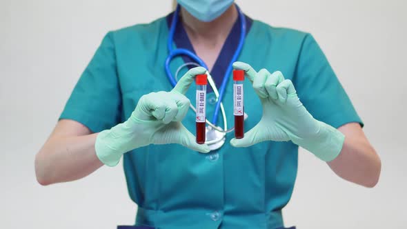 Medical Doctor Nurse Woman Wearing Protective Mask and Latex Gloves - Holding Blood Test Tube