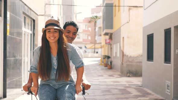 People, leisure and lifestyle concept happy young couple riding bicycle in the city - overjoyed