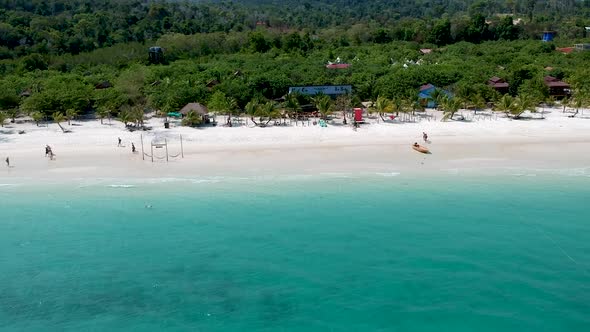 Aerial pan along white sand beach with turquoise blue sea in Koh Rong, Cambodia