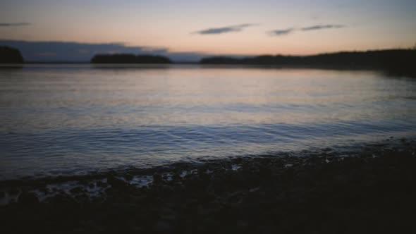 Handheld view of small waves hitting the coast,at a lake,at sunset, on a cold autumn evening