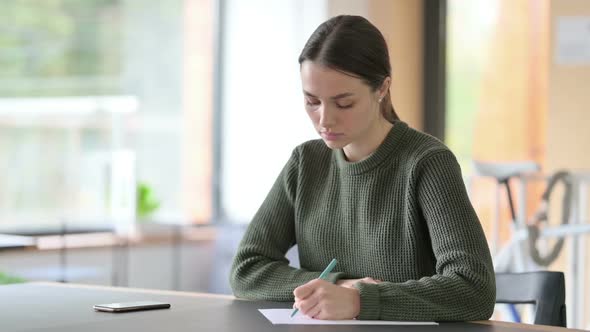 Young Woman Writing on Paper at Work