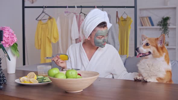 A Girl With a White Towel Put on Her Face a Green Mask During Blogging.