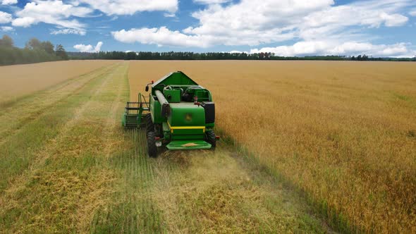 Drone flying over combine harvester working on wheat field