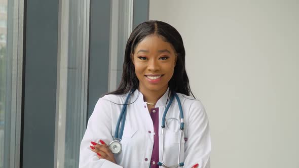 A Young African American Female Graduate in a White Medical Gown Smiles and Poses for the Camera