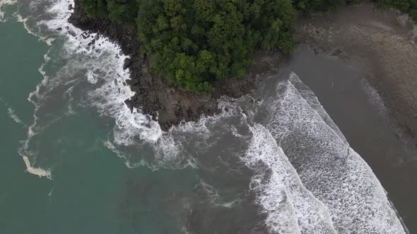 Wide top down aerial view of a beach in Costa Rica with rocks and trees